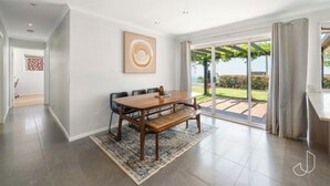 Amplia habitación con una gran mesa de comedor, un banco y vistas a un jardín a través de un ventanal.