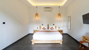 Une chambre à coucher avec un grand lit, des tables de chevet, un téléviseur à écran plat et des lampes suspendues.