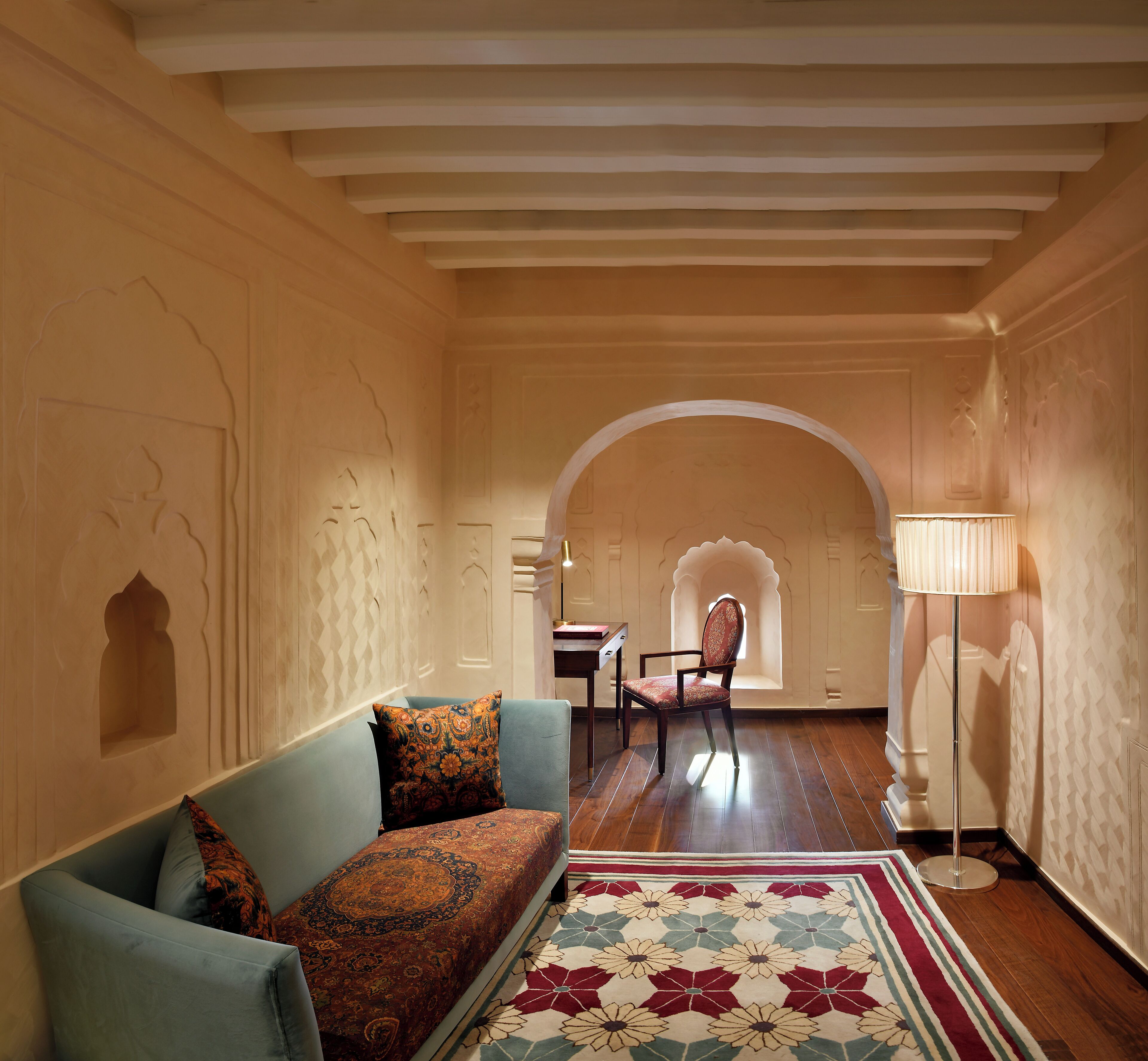 A room with a sofa, a patterned rug, a table, and a chair.