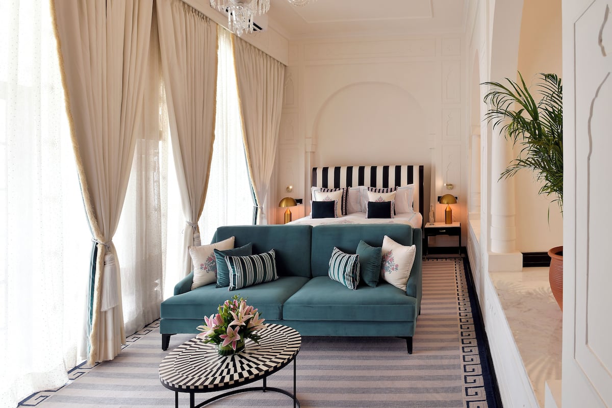 A spacious living room with a teal sofa, a round coffee table, and a chandelier.