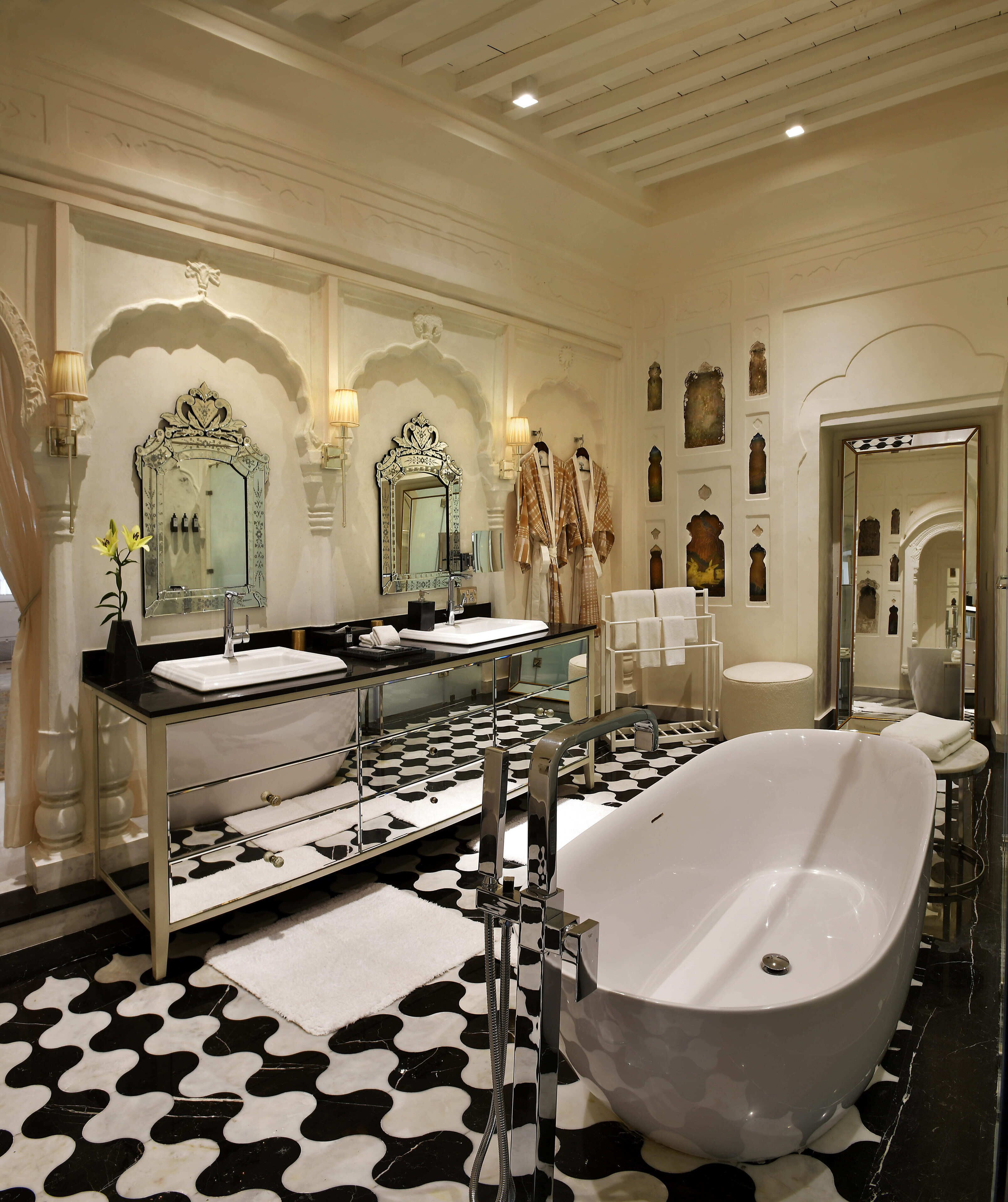 Een luxe badkamer met een vrijstaand bad, een dubbele wastafel met een grote spiegel en een vloer met een patroon.