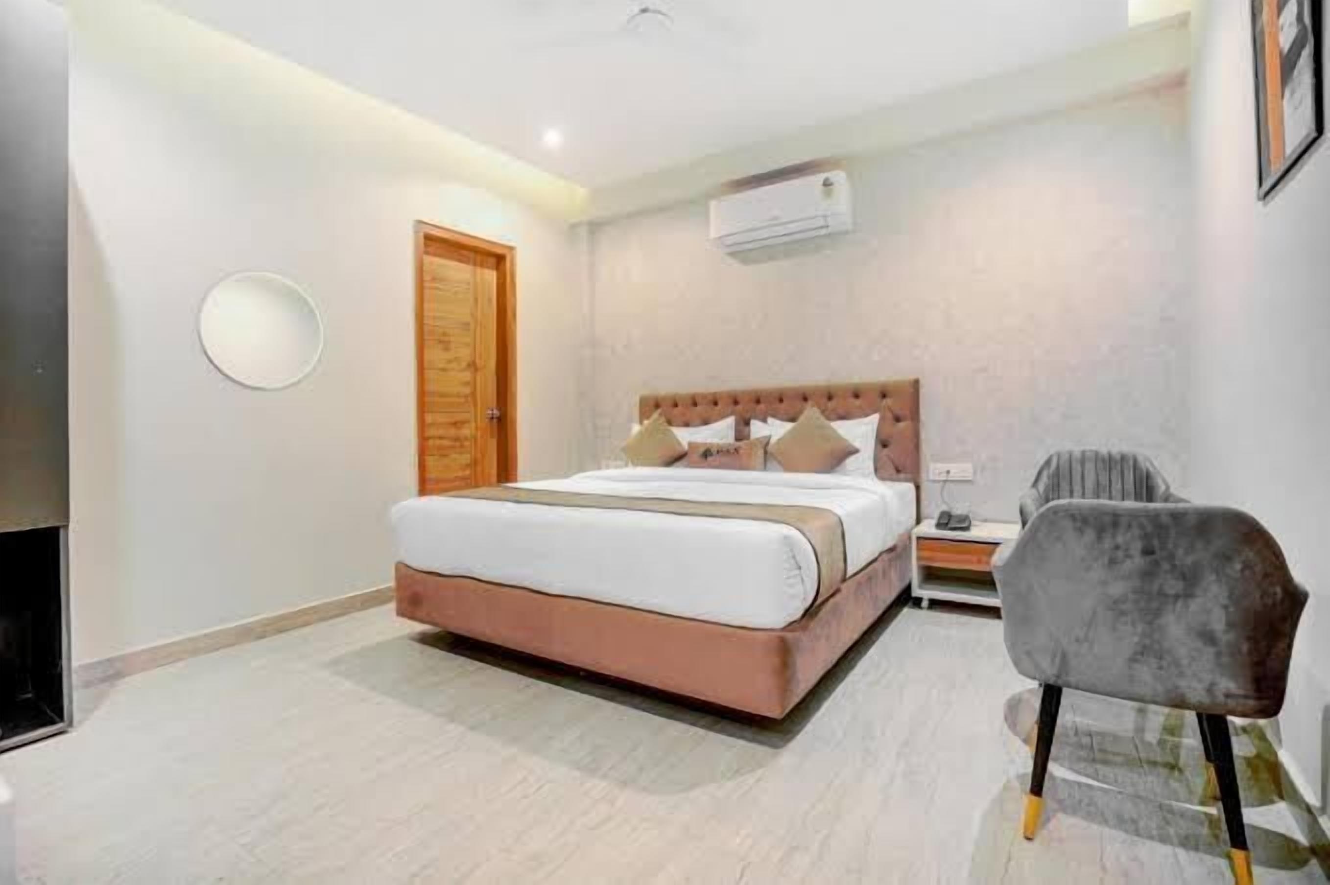A bedroom with a bed, a chair, a nightstand, and a wall-mounted air conditioner.