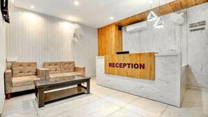 Una zona reception con scrivania in legno, un divano color beige e un tavolino da caffè in vetro.