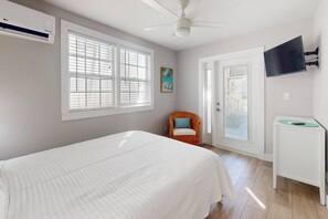 A bedroom with a bed, a chair, a TV, and a bathroom.