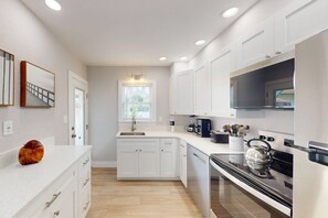 A modern kitchen with white cabinetry, a built-in oven, and a coffee maker.