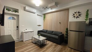 Una sala de estar moderna con un sofá, una mesa de centro y aire acondicionado integrado.