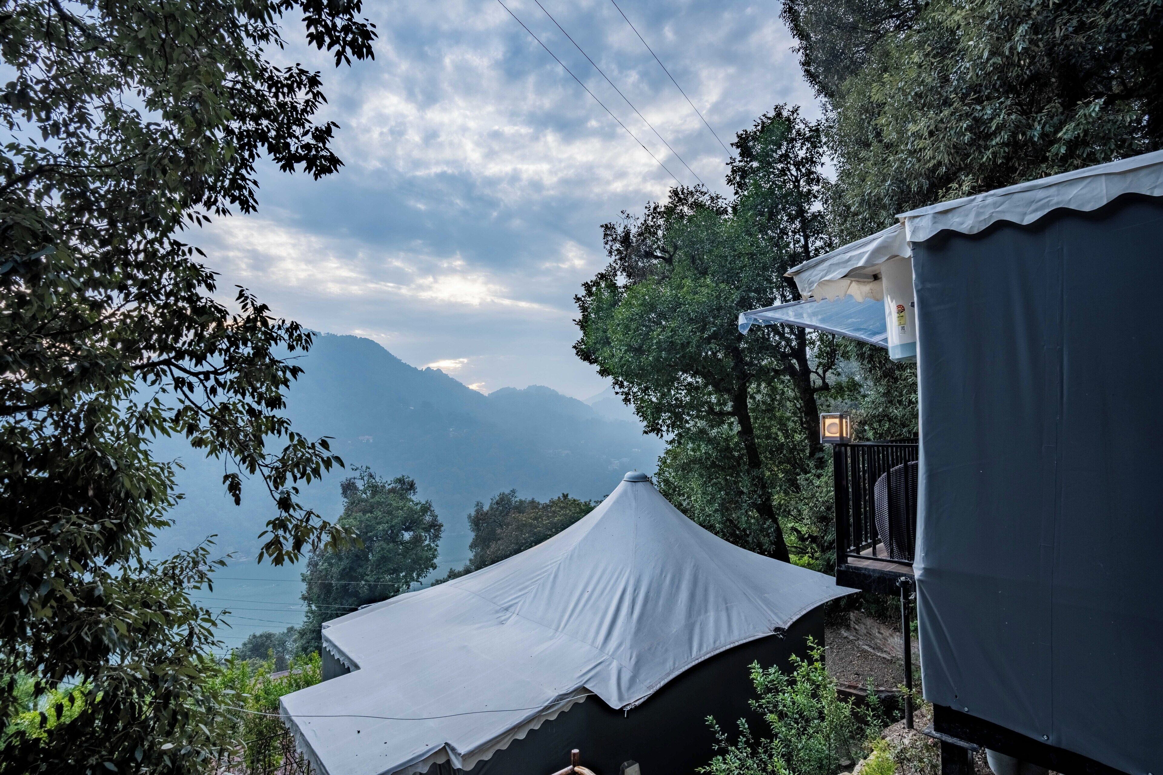 A tented area with a view of mountains and a lake.