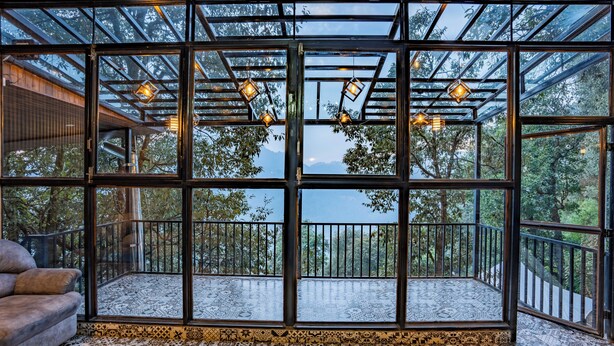 A room with large windows, a patterned floor, and hanging lights. - The Whispering Oaks (Nainital)