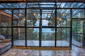 A room with large windows, a patterned floor, and hanging lights. - The Whispering Oaks (Nainital)