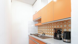 A compact kitchen with orange cabinets, a stainless steel sink, and a coffee maker. - Apartment near ski lift and ski bus in Brixen (Brixen)