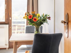 Enjoy a peaceful stay with a view, featuring a comfortable table and chair, and a beautiful vase with fresh flowers.