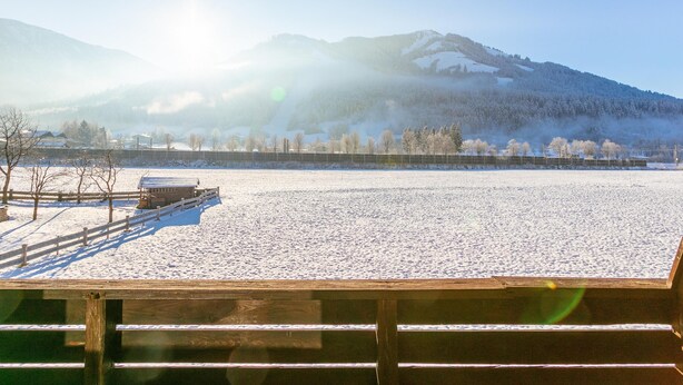 A snowy landscape with a wooden structure in the foreground and mountains in the background.