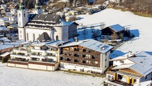 En snedækket by med en markant kirke og en stor bygning med flere balkoner.
