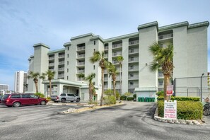 A multi-story hotel with balconies, palm trees, and a private parking area with a tow-away sign. - Walk to Coast: Condo in Daytona Beach Shores! (Daytona Beach Shores)