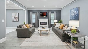 Una sala de estar moderna con dos sofás, una mesa de centro, chimenea y televisor de pantalla plana.