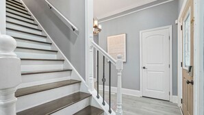 Una escalera con balaustres blancos y escalones de madera oscura que lleva a una plataforma.
