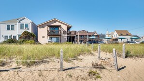 A beachfront property with a two-story house, a balcony, and a beach umbrella. - 'Beachfront 14' Condo on Old Orchard Beach (Old Orchard Beach)