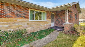 A brick house with a stone foundation, a front porch, and a small garden area. - Stay & Play: West Virginia Country Home! (Davisville)
