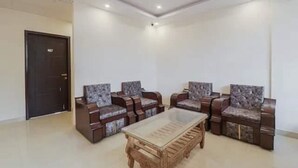 A spacious room with a ceiling fan, a large wooden table, and four upholstered chairs with patterned cushions. - Rabbit Hut Guest House By GRB (Dehradun)