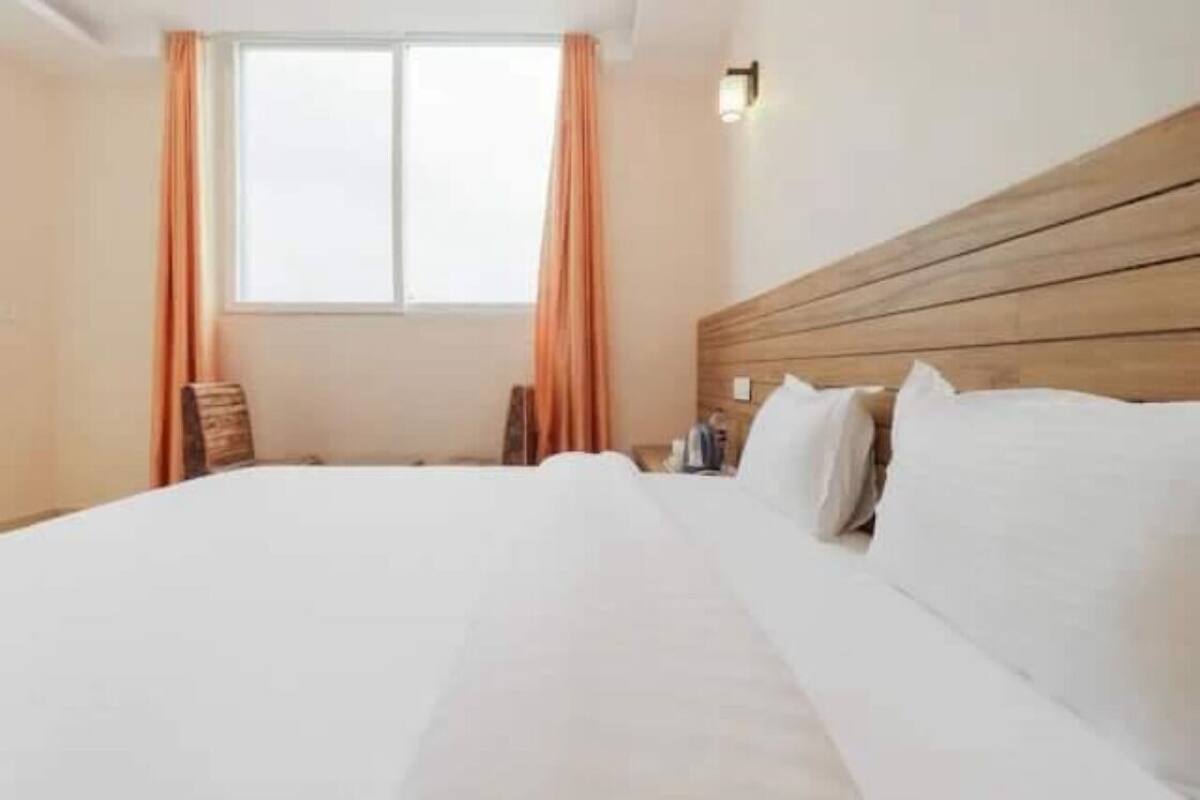 Hotellihuone, jossa on suuri sänky, puinen pääty ja ikkuna, jossa on verhot.