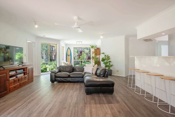 A modern living room with a sectional sofa, a wooden entertainment unit, and a bar area with stools.