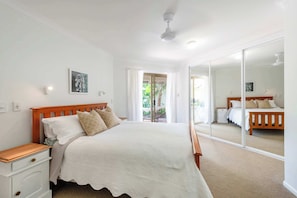 A bedroom with a bed, nightstand, and a large mirror.
