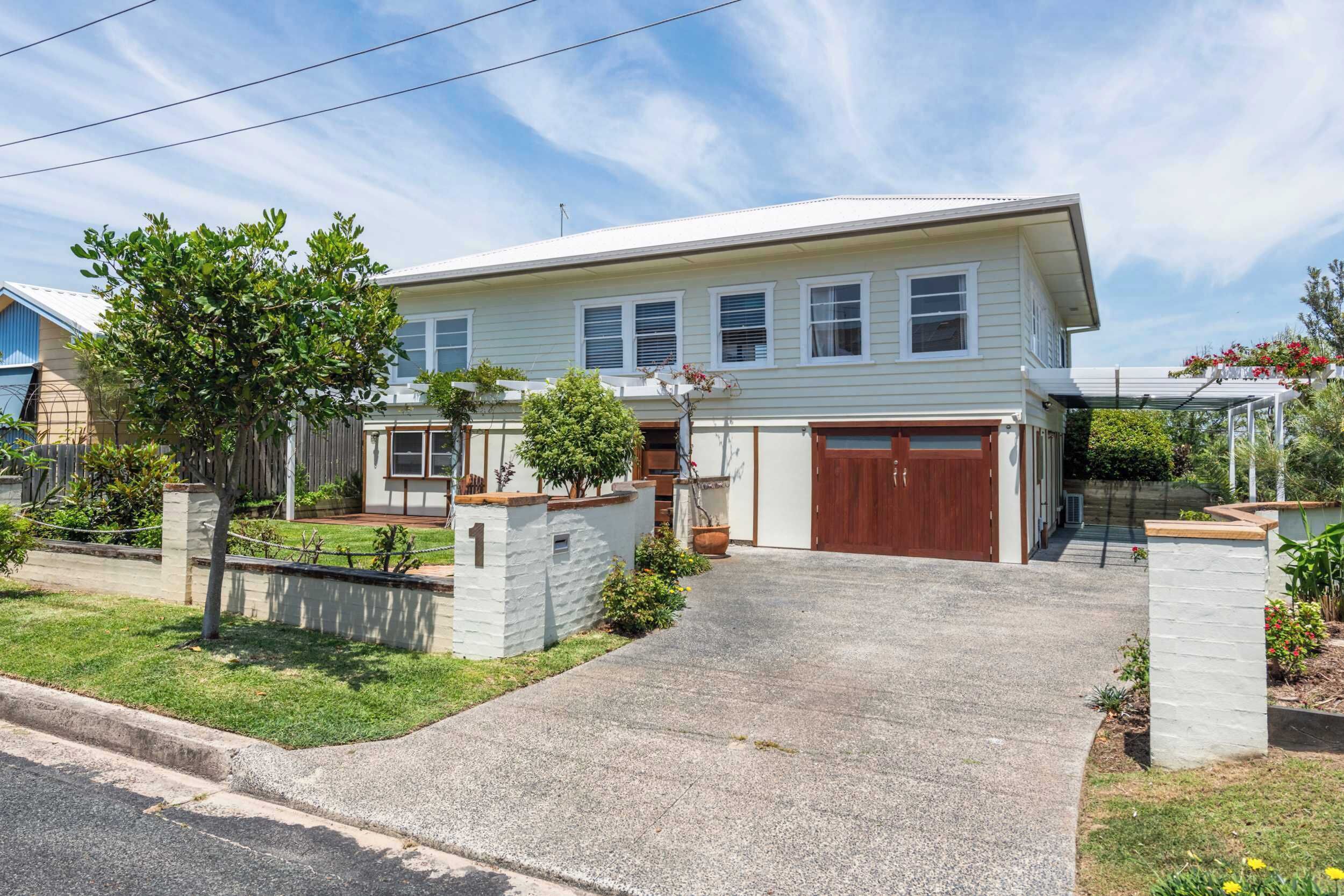 A two-story house with a garage, a driveway, and a well-maintained lawn.