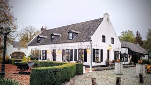 En traditionell vit byggnad med ett brant tak, svarta fönsterluckor och en innergård med kullerstenar.