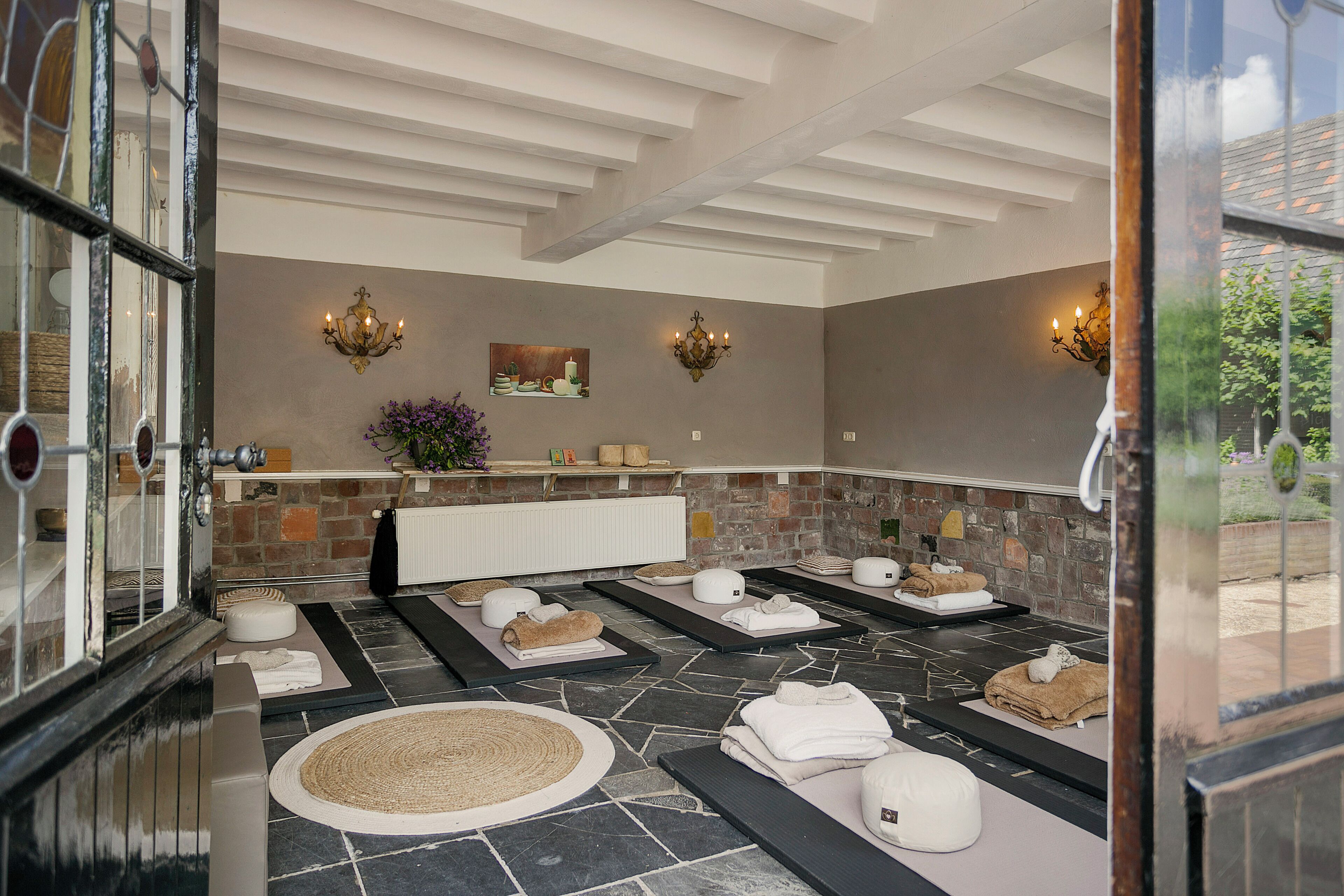 A spa room with stone flooring, multiple towel stations, and wall-mounted lighting fixtures.