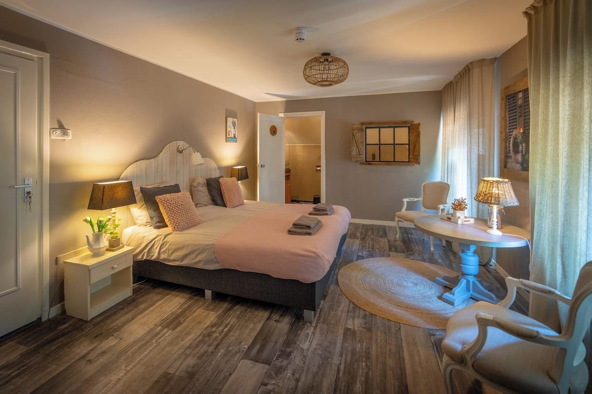 Une chambre à coucher avec un lit, des tables de chevet, une table ronde et des chaises.