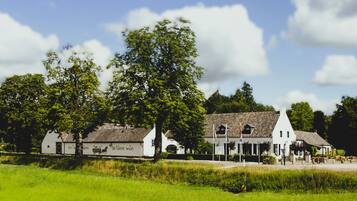 A traditional Dutch farmstead with multiple white buildings, including a barn and a house with a sloped roof.