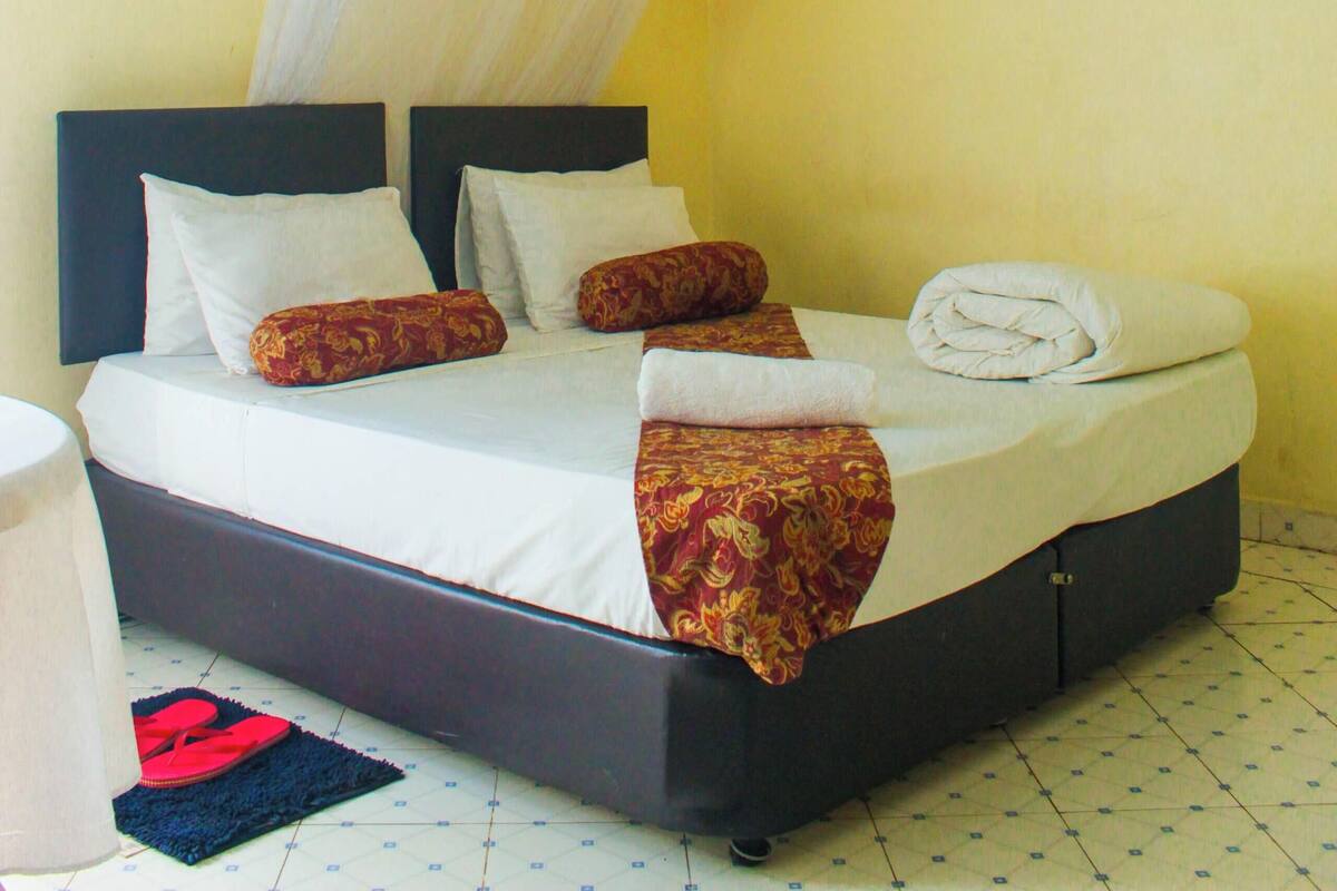 A bed with a canopy, pillows, and a folded towel.