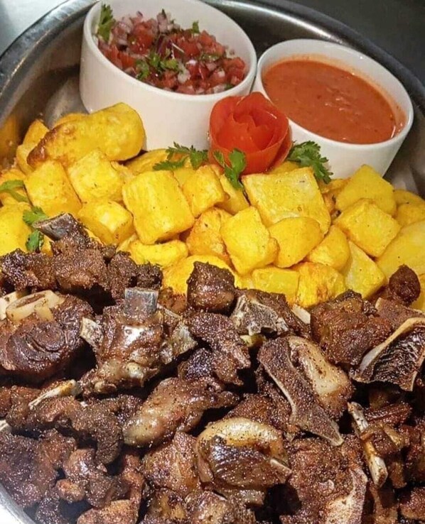 A meal with grilled meat and yellow potatoes, served with two types of salsa. - mirok gardens kisumu (Kisumu)