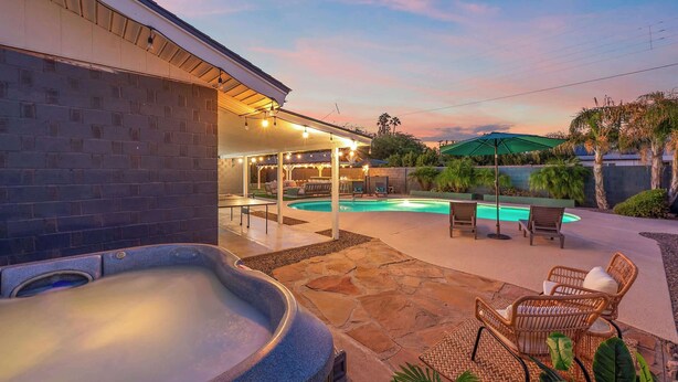 Un jacuzzi, mobiliario de exterior y una piscina en un patio trasero.
