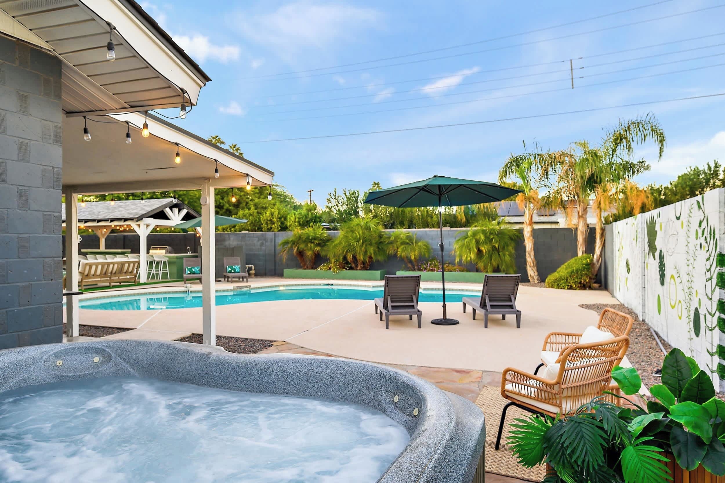 A backyard with a hot tub, a pool, and outdoor seating.