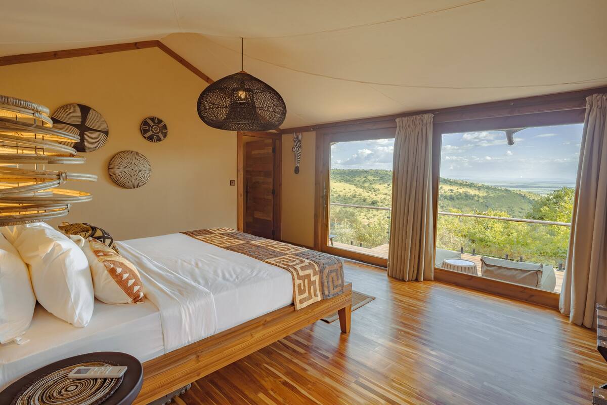 Ein geräumiges Schlafzimmer mit einem großen Bett, Holzboden und einem Balkon mit schöner Aussicht.