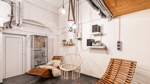 A room with a wooden bench, a macramé hanging chair, a glass cabinet, and a white door.
