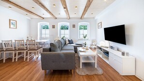 A modern living room with a sofa, dining table, chairs, a TV, and a fireplace.