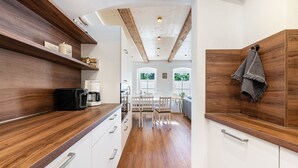 A modern kitchen with wooden countertops, white cabinets, and a dining area with a wooden table and chairs.