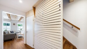 A hallway with a wooden floor, a white door, and a staircase with wooden steps.