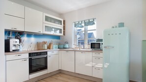 Una cocina moderna con armarios blancos, horno empotrado, microondas y refrigerador.