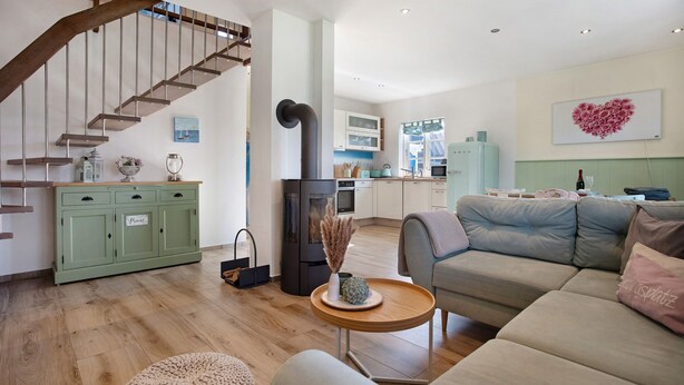 Una sala de estar moderna con una escalera, una cocina y una decoración de pared con forma de corazón.