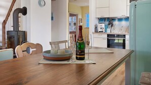 Una cocina con una mesa de madera, una botella de champán y un bol de fruta.