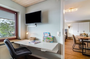 A modern room with a desk, chair, mounted TV, and books. - Apartment “Behling” with Mountain View, Private Terrace, and Wi-Fi (Frickingen)