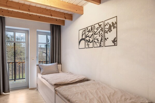 A bedroom with a bed, a window, a balcony with lights, and wall art.