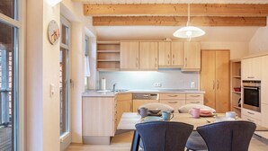 Una cocina moderna con armarios de madera, una mesa de comedor con sillas y una lámpara colgante.