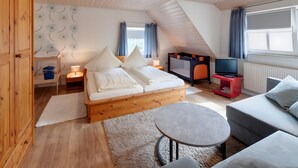 A room with a bed, a sofa, a TV, and a small table. - Apartment 'Glockenblume' with Shared Terrace, Shared Garden and Wi-Fi (Gerabronn)