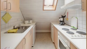 A compact kitchen with a window, a sink, a stove, and a microwave. - Apartment 'Gänseblümchen' with Shared Terrace, Shared Garden and Wi-Fi (Gerabronn)