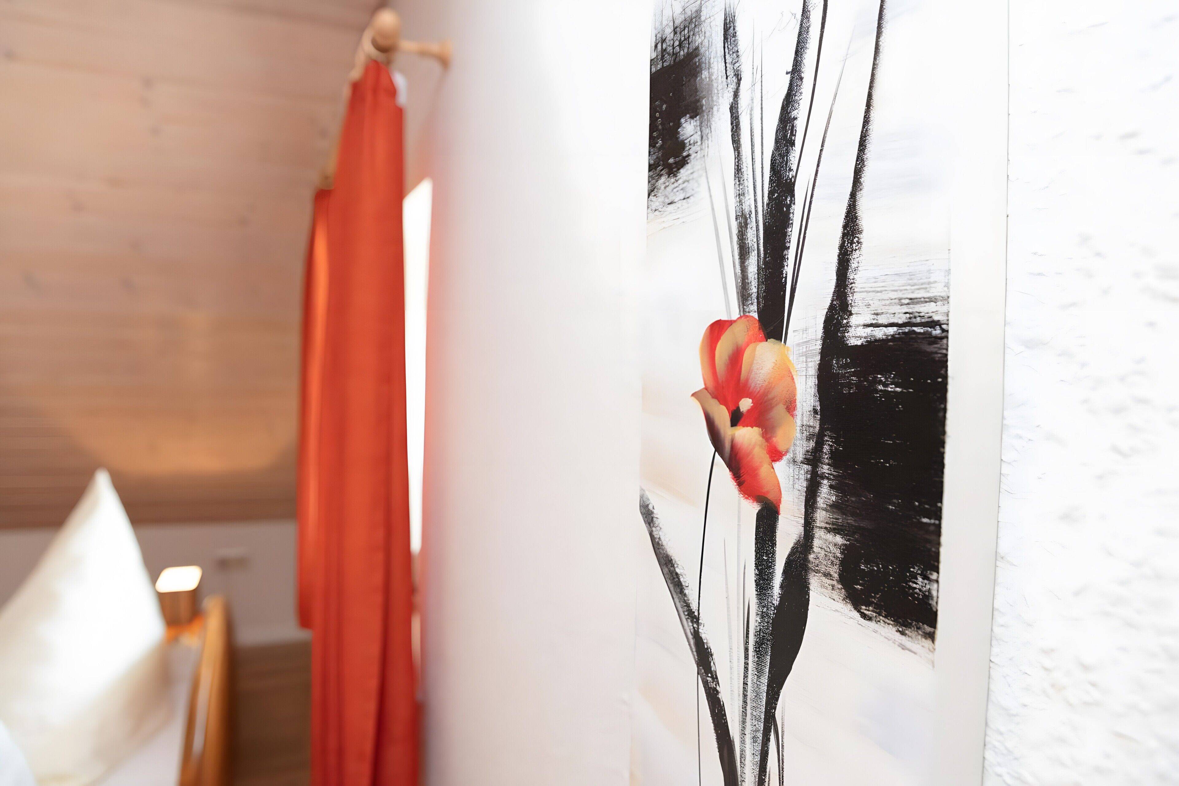 Une pièce avec un plafond en bois, un rideau rouge et un tableau représentant une œuvre d’art abstraite en noir et blanc.