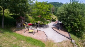 Une aire de jeux avec des balançoires, un toboggan et un petit abri.